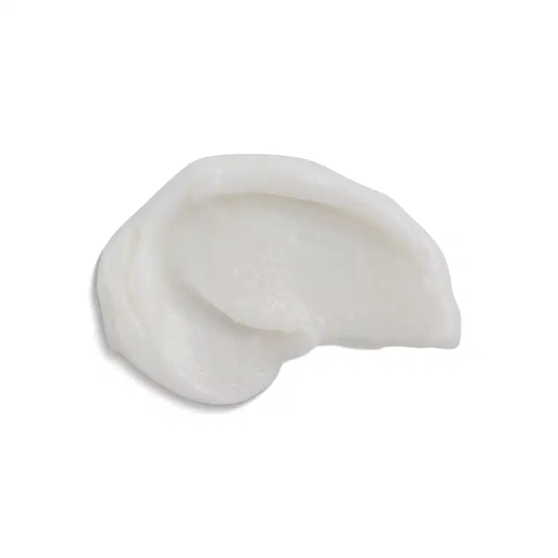 Produto com Consistência cremosa e cor branca. Forma arredondada e irregular, semelhante a uma concha ou pedra polida. Sem embalagem ou rótulos visíveis. Aparência simples e minimalista, focada na textura e forma orgânica do produto.
