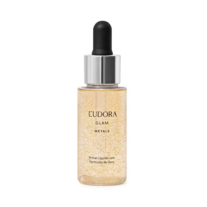 Primer líquido. Frasco transparente com tampa prateada e preta contendo um líquido dourado brilhante com partículas cintilantes. Rótulo dourado com o nome do produto e da linha. Embalagem simples destacando o aspecto metálico e iluminador do produto.