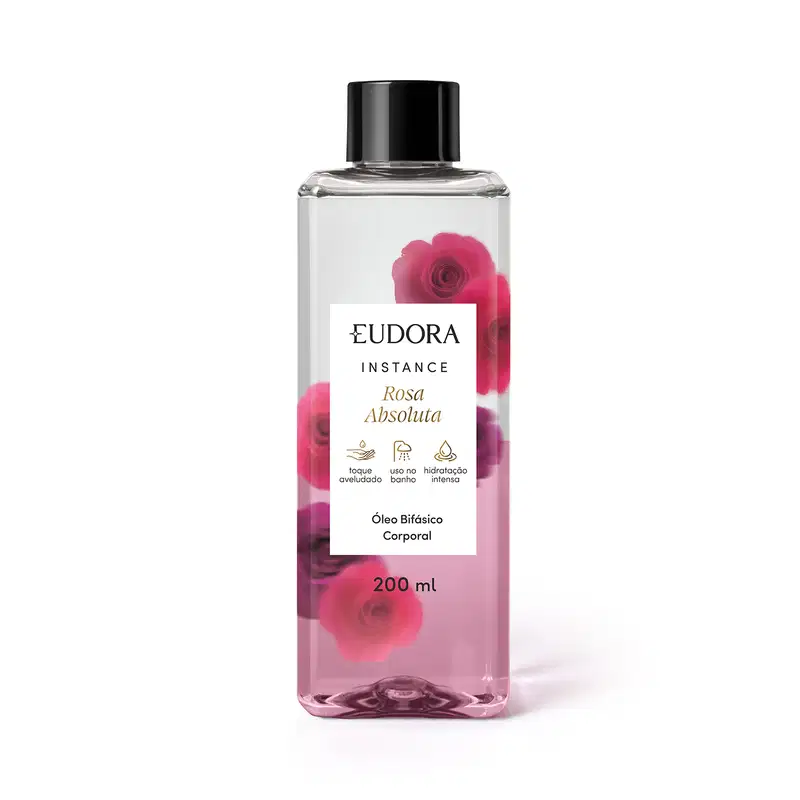 O produto apresentado é um óleo bifásico corporal da linha Instance Rosa Absoluta. O frasco é transparente, com um rótulo branco contendo o nome da marca, da linha e do aroma. A embalagem possui uma tampa preta e contém 200 ml do produto.