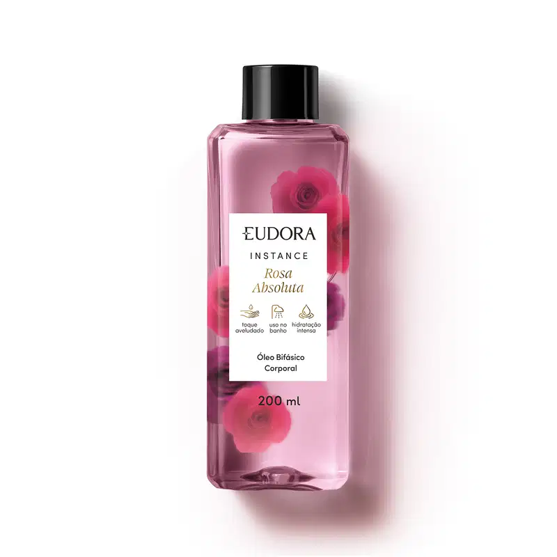 O produto apresentado é um óleo bifásico corporal da linha Instance Rosa Absoluta. O frasco é transparente, com um rótulo branco contendo o nome da marca, da linha e do aroma. A embalagem possui uma tampa preta e contém 200 ml do produto.