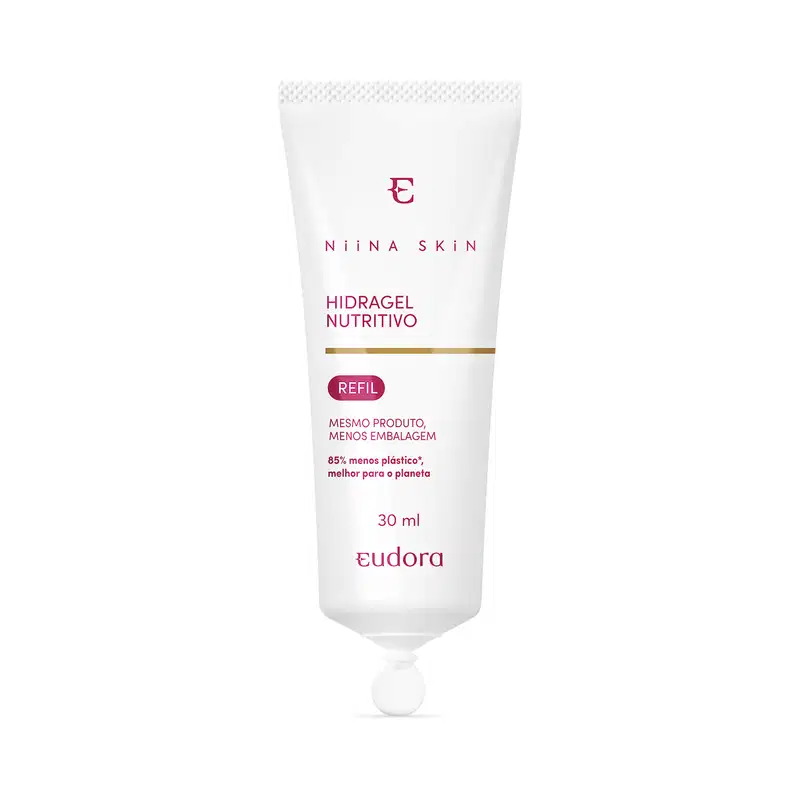 Embalagem plástica branca opaca em formato de tubo, com 30ml. Tampa na parte inferior e formato redondo, semi-gota, achatado. Rótulo com texto em rosa. Logotipo e nome da marca na parte inferior. Cores predominantes são branco, vermelho e dourado.