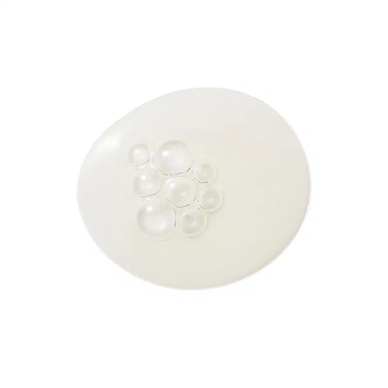 Textura transparente e brilhante de um item de skincare, com pequenas bolhas de ar distribuídas uniformemente sobre uma superfície lisa e clara.