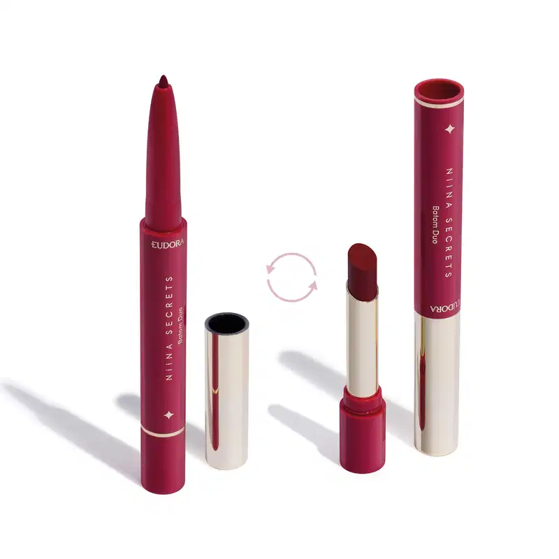 O produto apresentado na imagem é um batom da marca Niina Secrets Eudora. São dois produtos em um: uma lapiseira delineadora com a ponta afiada e o batom em formato stick. Todos os itens possuem detalhes em dourado e rosa.