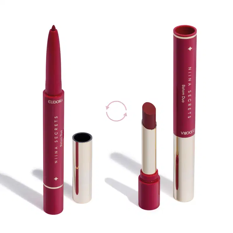 O produto apresentado na imagem é um batom da marca Niina Secrets Eudora. São dois produtos em um: uma lapiseira delineadora com a ponta afiada e o batom em formato stick. Todos os itens possuem detalhes em dourado e rosa.