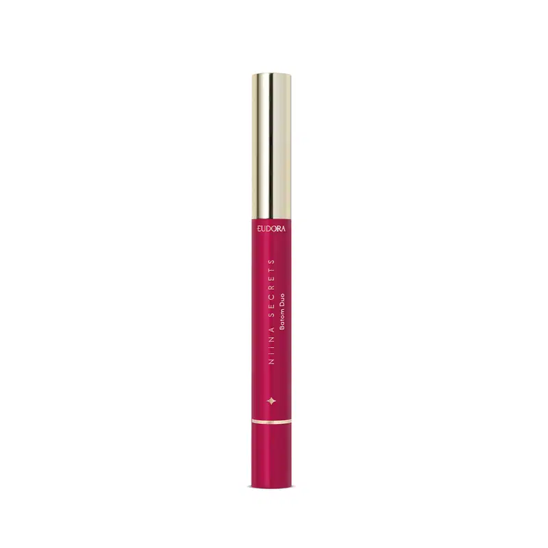 O produto apresentado é um batom da marca Eudora, da linha Niina Secrets. O batom possui embalagem tubular de cor rosa vibrante, com o nome da marca e da linha impressos na superfície. A tampa do batom é dourada.