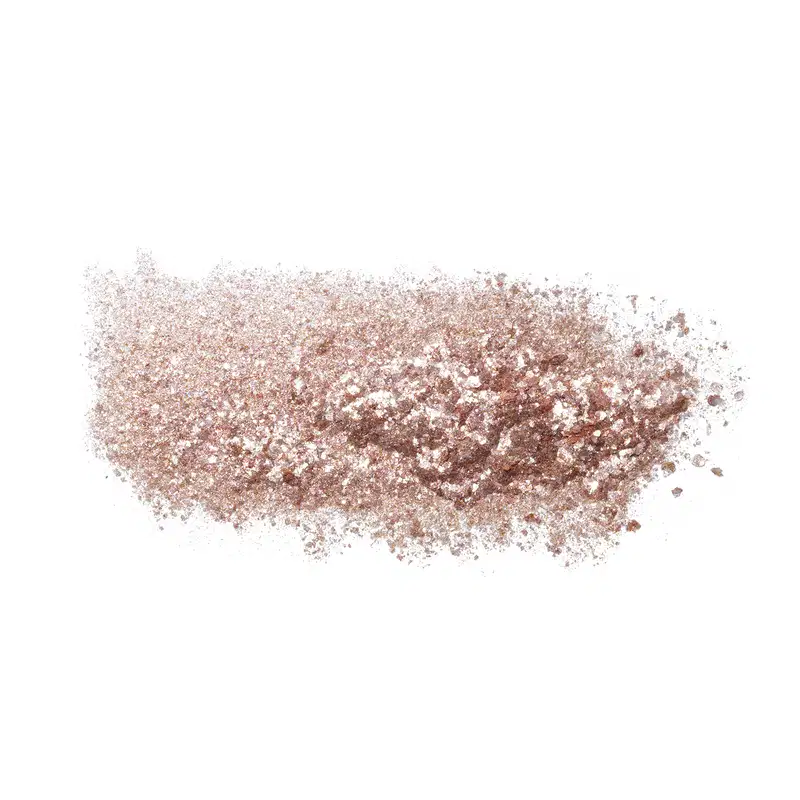 Textura do produto Glitter Glam Paetê. A embalagem não é visível, mas o produto é apresentado em uma superfície branca, com uma textura granulada e brilhante, sugerindo uma fórmula com partículas cintilantes ou brilhantes.