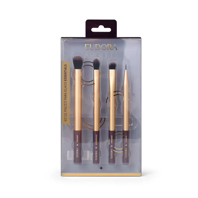 O produto é um kit de pincéis de maquiagem da marca Eudora. O kit contém 4 pincéis com cabos dourados e detalhes em preto. Os pincéis possuem diferentes formatos e tamanhos, para diferentes aplicações. A embalagem é uma caixa plástica transparente.