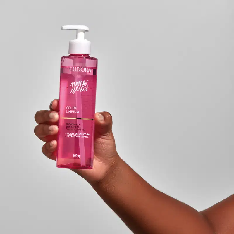 Frasco do produto Gel de Limpeza Niina Secrets sendo segurado por uma mão feminina.