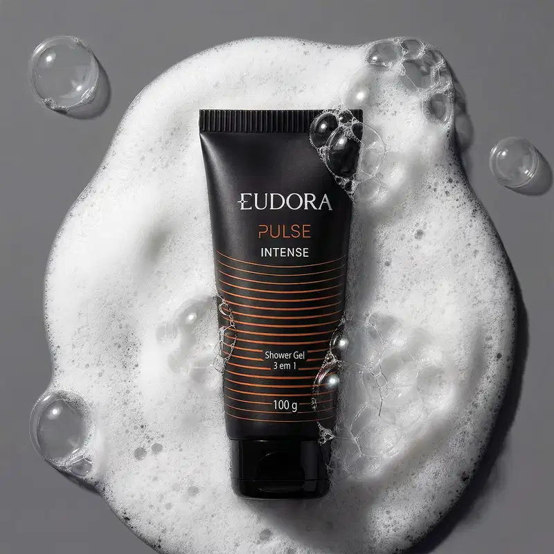 Imagem mostra um tubo de gel de banho da marca Eudora, com a linha "Pulse Intense", com a textura de bolhas de sabão e espuma ao fundo, sugerindo um contexto de higiene e cuidados pessoais.