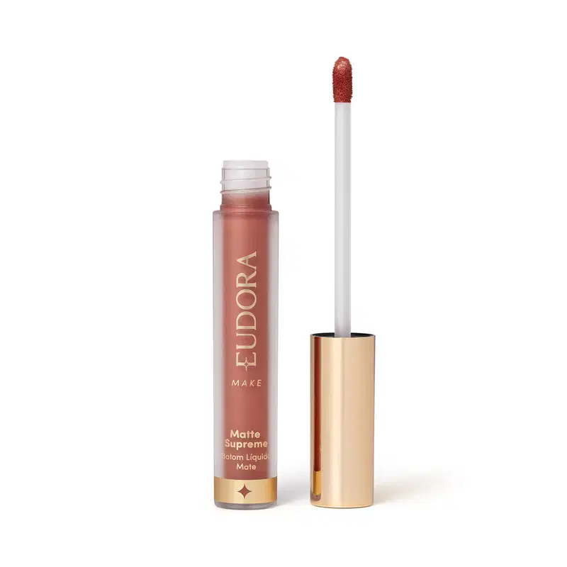 Batom Líquido Matte Supreme em embalagem transparente com tampa dourada e aplicador do tipo bastão. Produto com design minimalista e rótulo dourado no frasco.