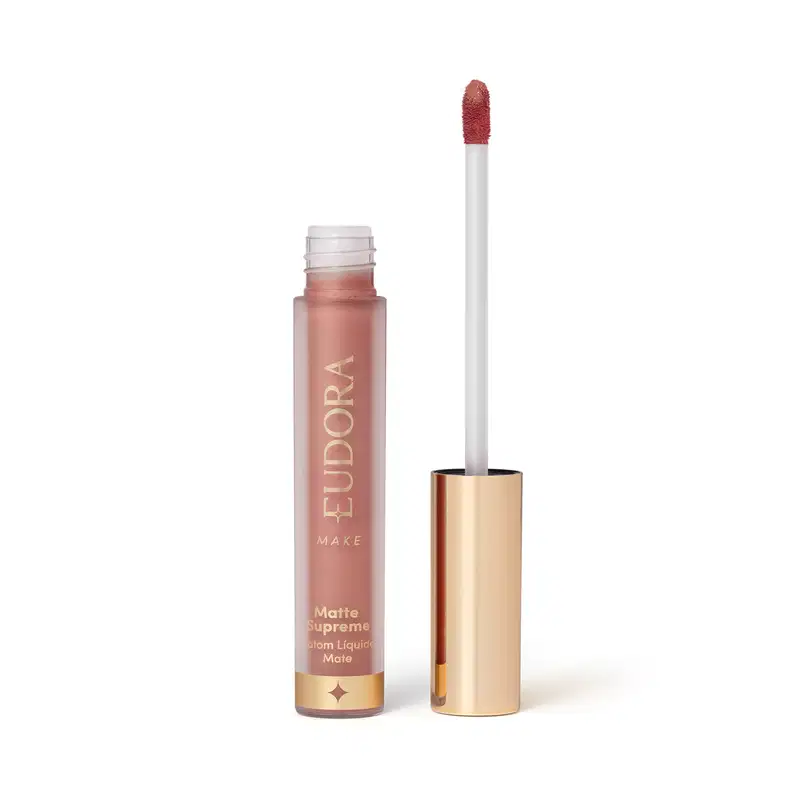 Batom Líquido Matte Supreme em embalagem transparente com tampa dourada e aplicador do tipo bastão. Produto com design minimalista e rótulo dourado no frasco.