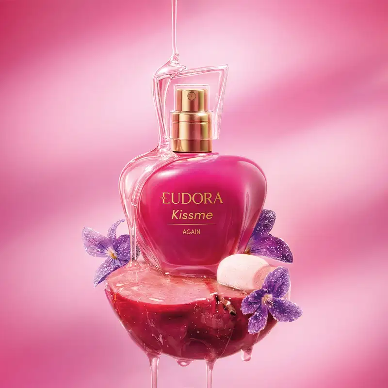 Frasco de item de perfumaria da marca Eudora com nome Kiss Me Again em fundo rosa com flores roxas de violeta, marshmallow e maçã.