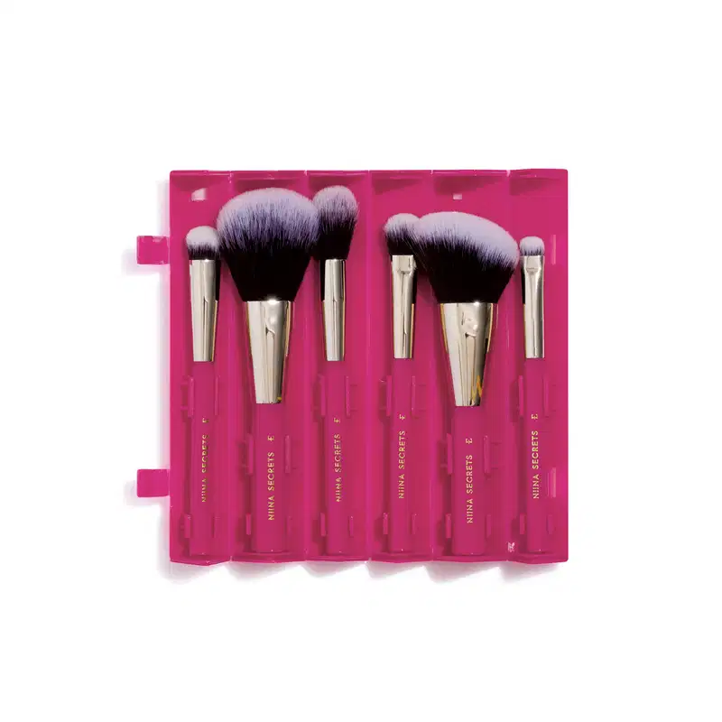 Estojo de pincéis de maquiagem Niina Secrets com seis pincéis de cerdas pretas e cabos dourados em embalagem rosa pink com compartimentos individuais.