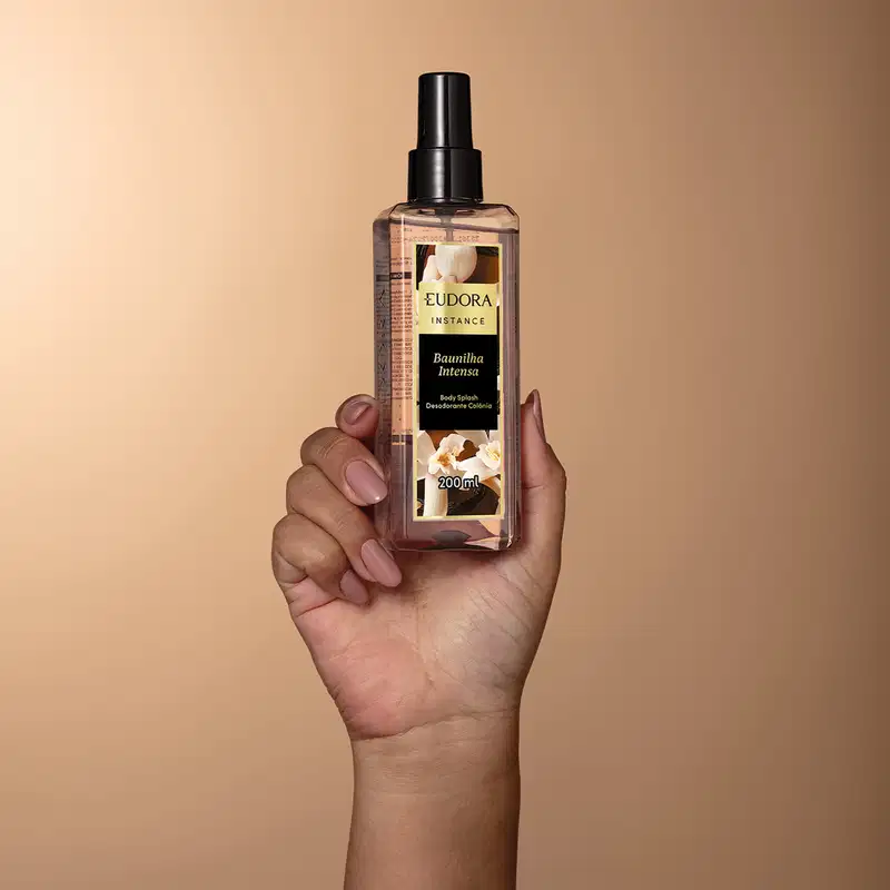 Imagem de um frasco de desodorante colônia body splash da marca Eudora Instance, com design elegante e moderno, em um ambiente de fundo bege, sugerindo um contexto de cuidados pessoais e bem-estar.