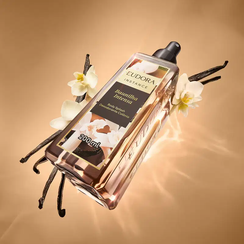 Ambiente de beleza com fragrância floral e notas amadeiradas. Embalagem elegante da marca Eudora Instance, com frasco transparente e ao fundo elementos da baunilha. 