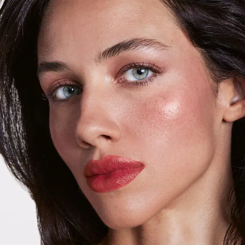 Close no rosto de uma mulher branca com a aplicação do produto nos lábios.
