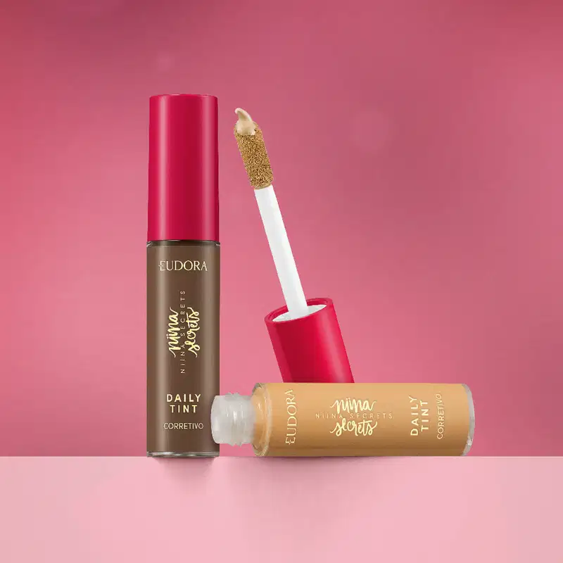 Dois produtos de maquiagem Eudora Niina Secrets com embalagem transparente e tampa rosa. Cada corretivo Daily Tint é de um tom diferente.
