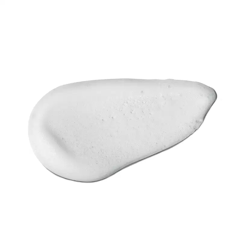 O produto apresenta uma textura suave, cremosa e uniforme, com uma aparência espumosa e brilhante. Sua superfície é areada, com pequenas bolhas visíveis. A cor predominante é o branco.