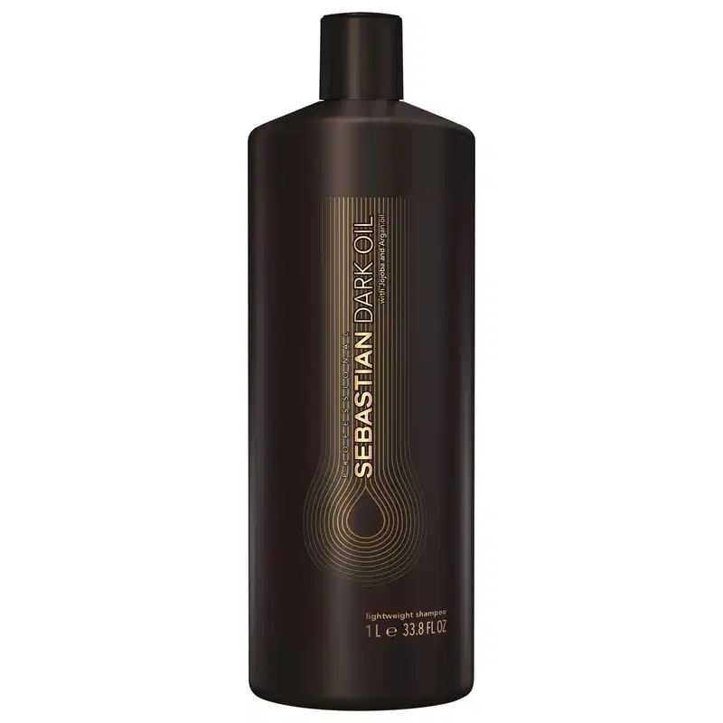 Shampoo leve da marca Sebastian Professional. Embalagem plástica marrom escura opaca com detalhes em dourado. Rótulo com o nome da marca e do produto "Sebastian Dark Oil" em letras douradas e estilizadas.