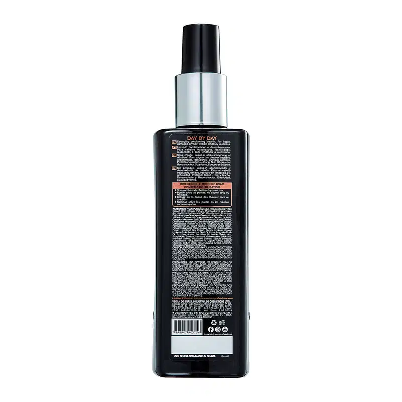 A imagem mostra um frasco plástico preto com uma tampa prateada. É um produto para cabelos chamado "Day by Day". O rótulo na parte traseira do frasco contém informações detalhadas sobre o produto, como instruções de uso, ingredientes e avisos.