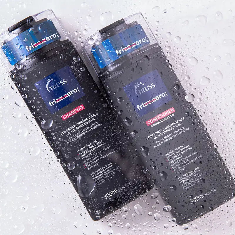 Produtos para cabelo da marca Truss, embalagens plásticas transparentes retangulares. Dois frascos de shampoo de 300ml cada, com rótulos azuis e vermelhos contendo informações do produto como "Shampoo" e "Condicionador para frizz".