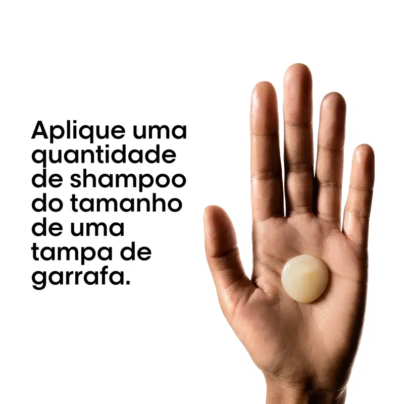 Produto de shampoo em embalagem esférica, com texto em português indicando a quantidade de produto e o tipo de tampa. Imagem mostra a mão de uma pessoa segurando o produto.