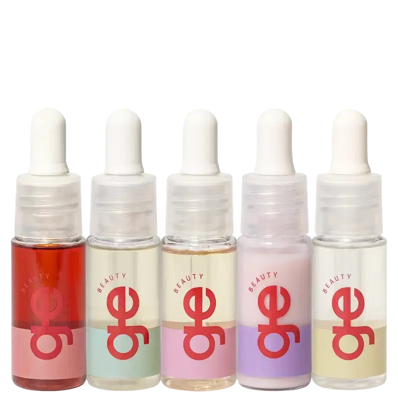 Cinco frascos com contagotas de GE Beauty em cores variadas: vermelho, bege, rosa claro, roxo e amarelo claro. Embalagens transparentes com rótulos vermelhos e tampas brancas arredondadas.