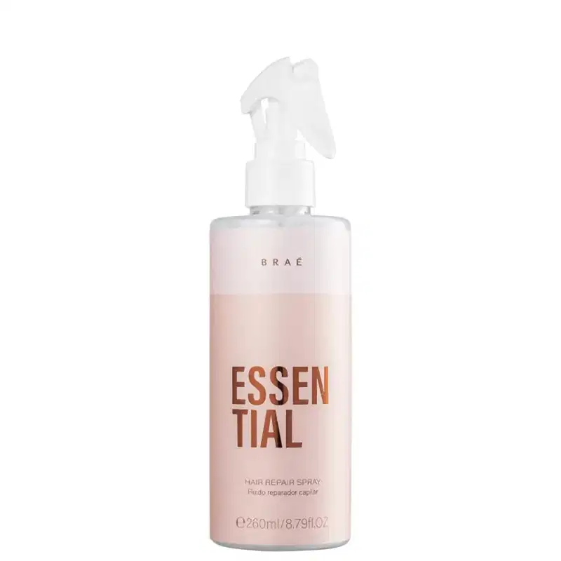 Produto de reparação capilar em spray da marca Braé. Embalagem plástica na cor rosa claro. Rótulo com o nome do produto "Essential" em letras marrons grandes e a descrição "Hair Repair Spray" em letras menores.