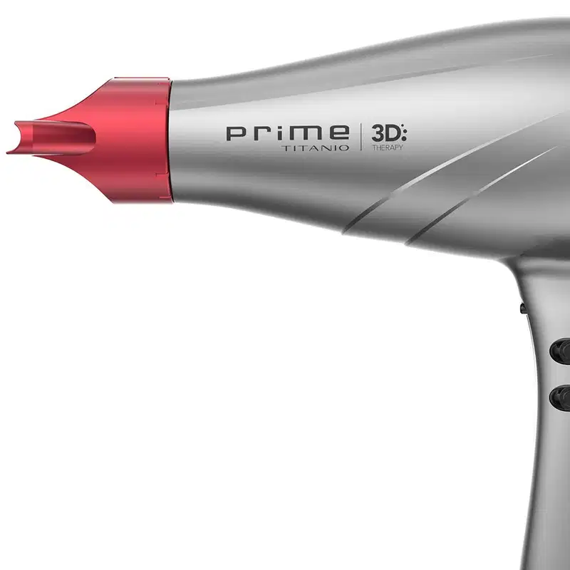 A imagem traz o secador de cabelo da GA.MA Italy Prime 3D Titanio. O acessório possui um corpo alongado e aerodinâmico em plástico cinza e detalhes em vermelho com o bico concentrador de ar removível na ponta.
