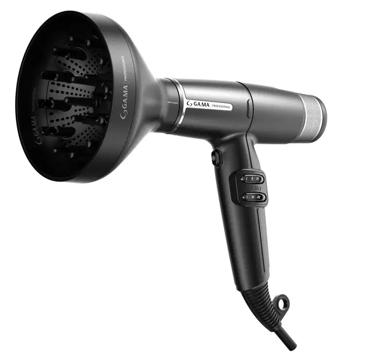 A imagem mostra o secador de cabelo profissional da marca GA.MA Italy. Els possui corpo preto e cilíndrico com detalhes metálicos prateados. Traz um difusor grande e arredondado com aberturas perfuradas. Cabo ergonômico e botões digitais.