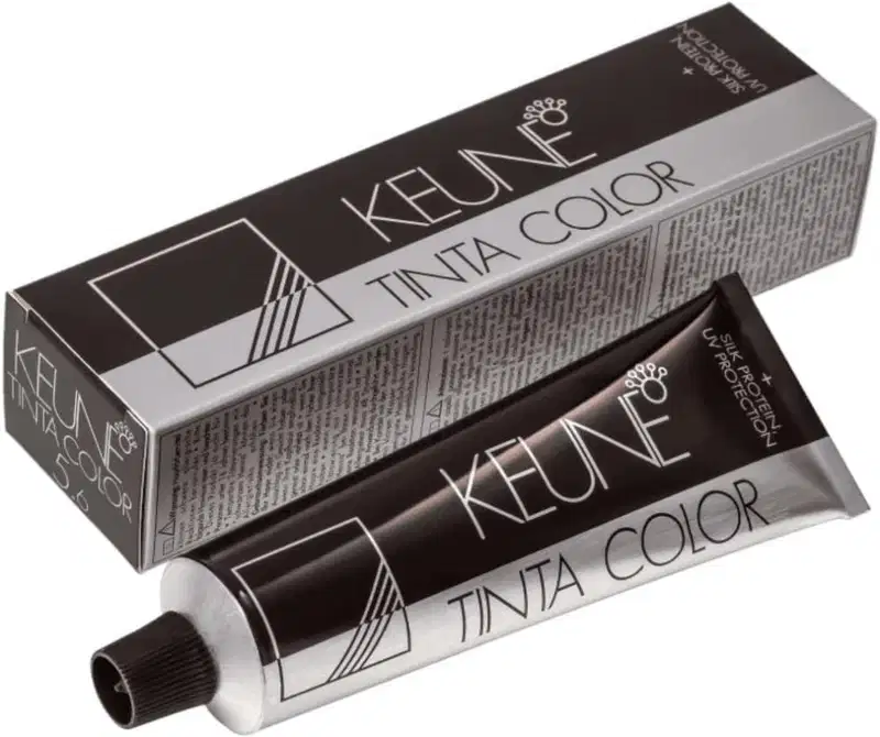 Produto de coloração permanente para cabelos Tinta Color da marca Keune. Embalagem retangular preta com detalhes em branco contendo o nome do produto e da marca.