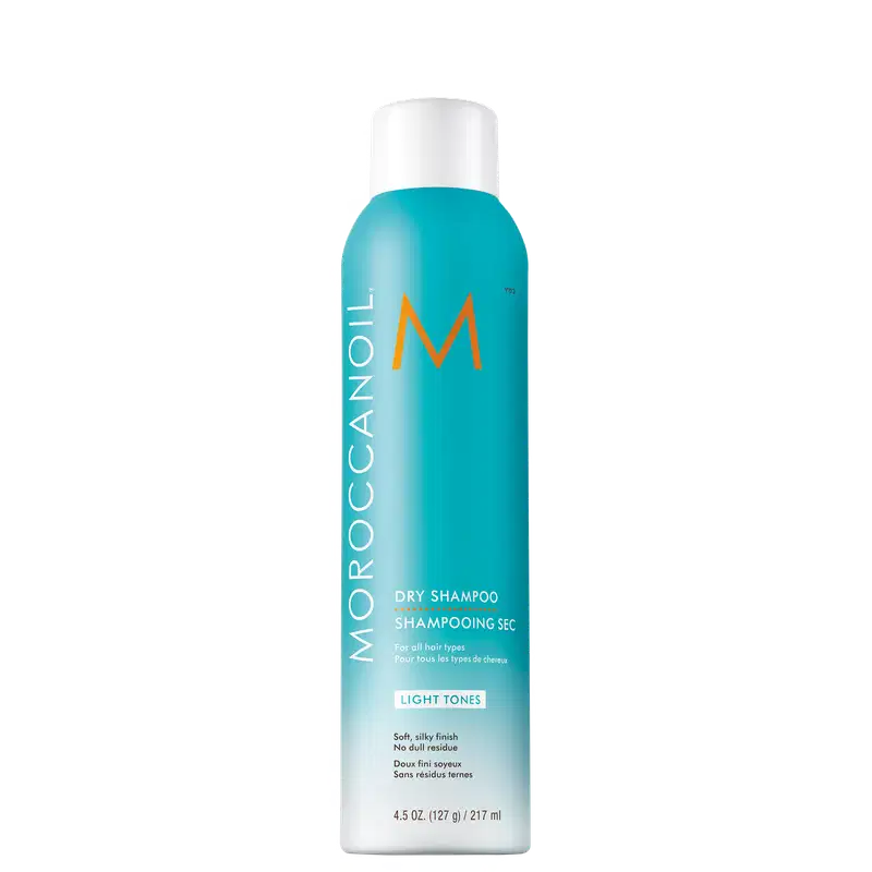 Frasco de shampoo seco Moroccanoil na cor azul-turquesa, com logotipo laranja e texto "Dry Shampoo" em destaque. Embalagem cilíndrica com tampa branca, indicando ser um produto para todos os tipos de cabelo.
