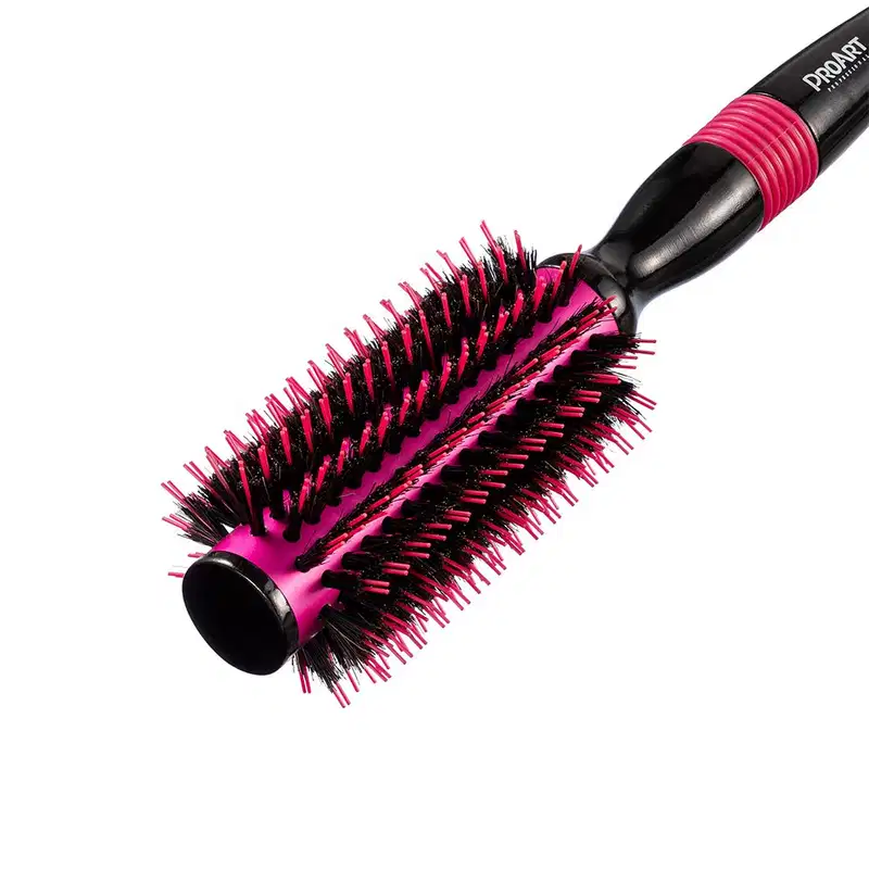 A imagem mostra a escova de cabelo em formato arredondado. Ela possui um corpo preto com cerdas rígidas e densas em tons de rosa vibrante e preto. Design moderno e ergonômico com cabo emborrachado rosa.