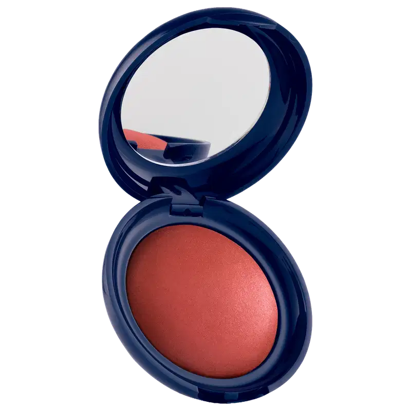 Blush em pó com embalagem redonda azul-marinho, espelho integrado na tampa e produto em tom laranja-avermelhado com acabamento luminoso.