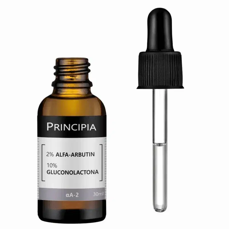 Frasco de vidro âmbar com conta-gotas contendo um líquido dourado. Rótulo branco com o texto "Principia" e "2% Alfa-arbutin e 10% Gluconolactona". Embalagem de plástico preto fosco.