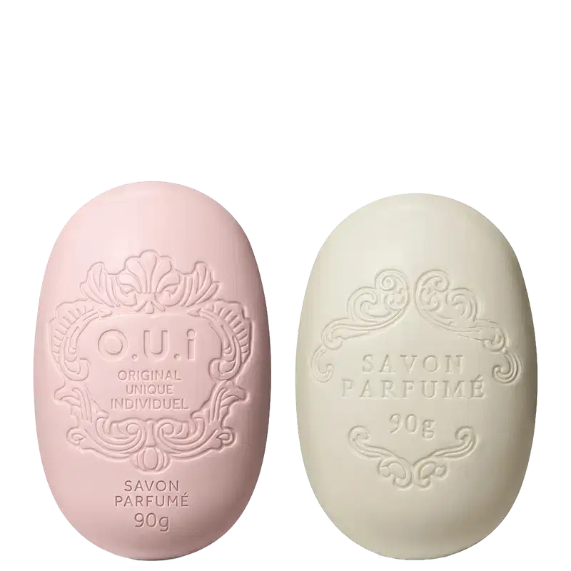 Dois sabonetes O.U.i em formato oval com relevos decorativos. À esquerda, sabonete rosa com inscrição "O.U.i Original Unique Individuel" e "Savon Parfumé 90g". À direita, sabonete bege com texto "Savon Parfumé 90g".