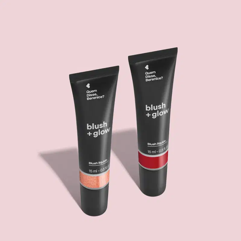 Imagem de duas bisnagas de blush líquido Blush +Glow, sendo o Rosedourex na cor rosa e o Lichiali na cor vermelha. As embalagens são pretas com parte transparente, mostrando a cor do produto, e letras brancas. O fundo da imagem é neutro com sombreado.