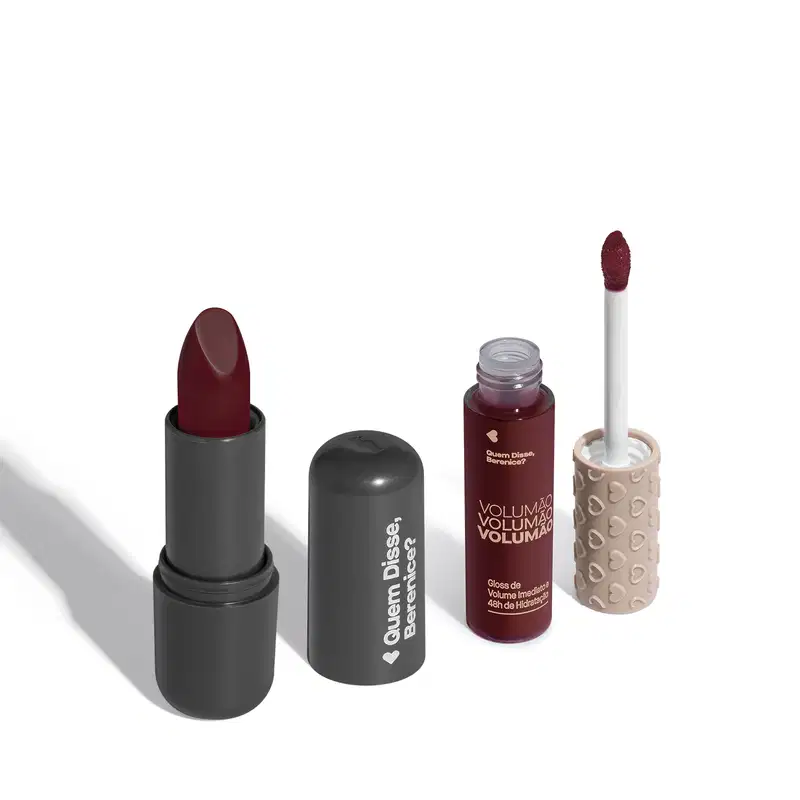 Batom na cor vinho com embalagem cinza e letras brancas e gloss labial de volume imediato Volumão em embalagem transparente e conteúdo na cor cereja com tampa cinza e aplicador vermelho escuro. Ambos da marca Quem Disse, Berenice?.