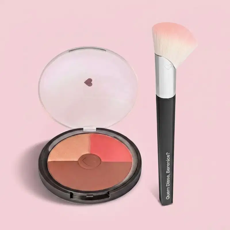 Paleta de blush compacta com quatro tons em tons de laranja e rosa, acompanhada de um pincel de maquiagem da marca Quem Disse, Berenice?, em fundo rosa.