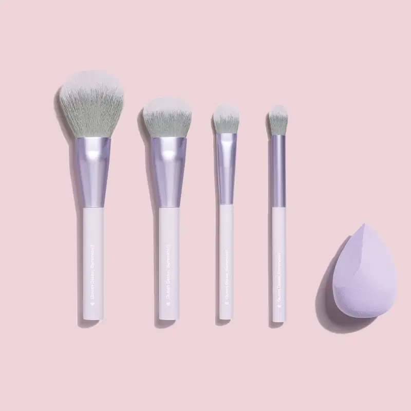 O produto mostrado é um conjunto de quatro pincéis de maquiagem da marca Quem Disse, Berenice? Os pincéis possuem cabos plásticos lisos na cor lilás claro e cerdas sintéticas de tom acinzentado.