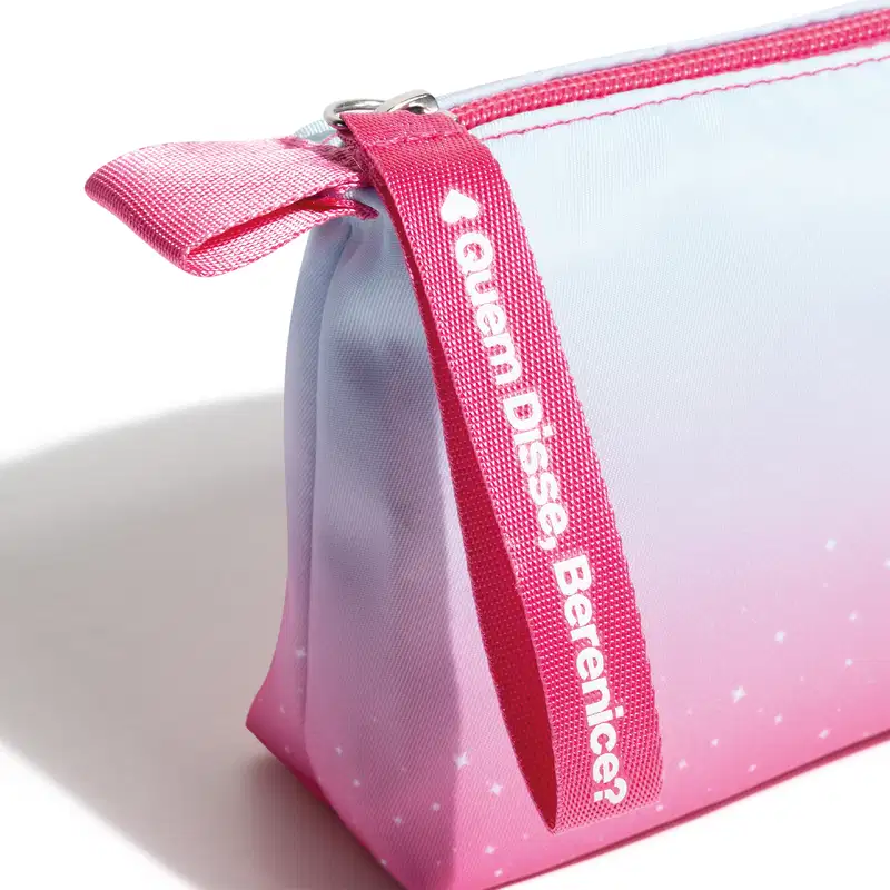 Necessaire de maquiagem rosa claro com detalhes de brancos. Alça de zíper rosa com o texto "Dos Sonhos Perfeitos" impresso. Feita de material têxtil com acabamento brilhante. Formato retangular com cantos arredondados. Design compacto e portátil