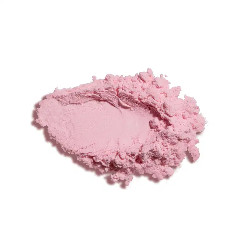 Textura de pó compacto fino de cor rosa, com aspecto seco, espalhada sobre superfície branca.