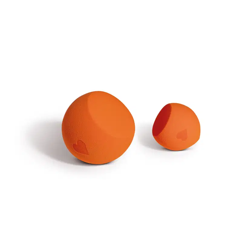 Dois objetos esféricos de cor laranja, com um coração vermelho impresso em um deles. São produtos de beleza da marca Quem Disse, Berenice?