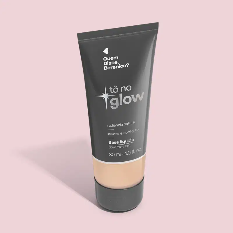 O produto apresentado é uma base líquida da marca Tô no Glow, com embalagem em tubo plástico preto e branco. O rótulo exibe o nome da marca e a descrição "Radiância natural, leveza e conforto". O produto é classificado como "Base líquida".