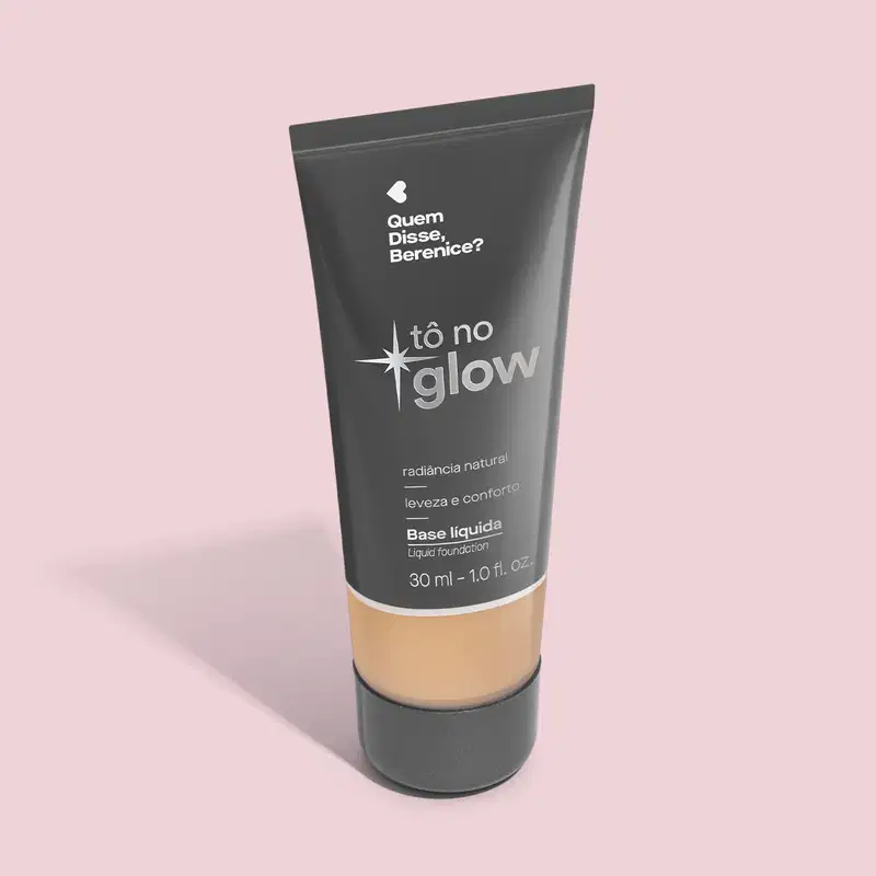 Base líquida em bisnaga preta com base transparente onde é possível ver o tom do produto. Fundo rosa.