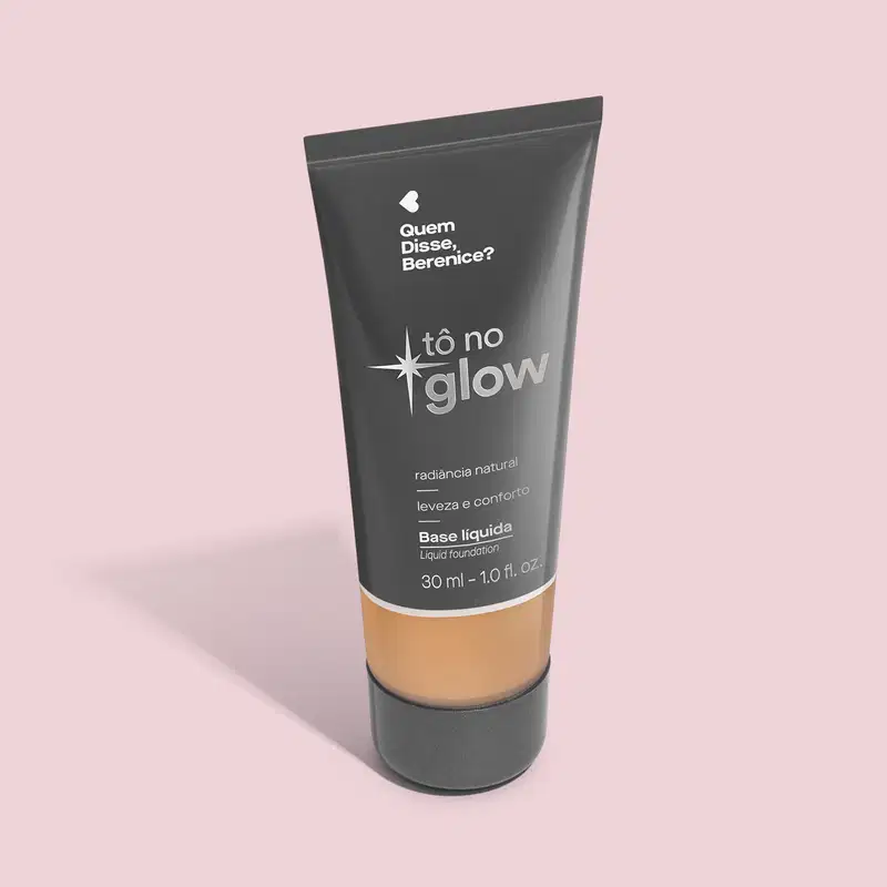 O produto apresentado é uma base líquida da marca Tô no Glow, com embalagem em tubo plástico preto e branco. O rótulo exibe o nome da marca e a descrição "Radiância natural, leveza e conforto". O produto é classificado como "Base líquida".