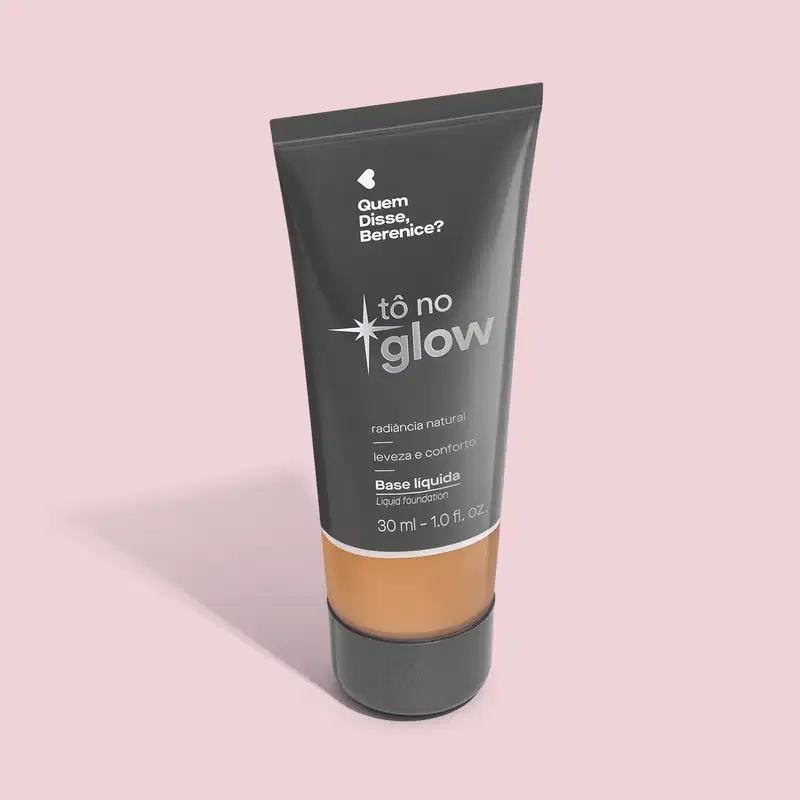 O produto apresentado é uma base líquida da marca Tô no Glow, com embalagem em tubo plástico preto e branco. O rótulo exibe o nome da marca e a descrição "Radiância natural, leveza e conforto". O produto é classificado como "Base líquida".