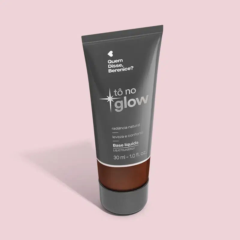O produto apresentado é uma base líquida da marca Tô no Glow, com embalagem em tubo plástico preto e branco. O rótulo exibe o nome da marca e a descrição "Radiância natural, leveza e conforto". O produto é classificado como "Base líquida".