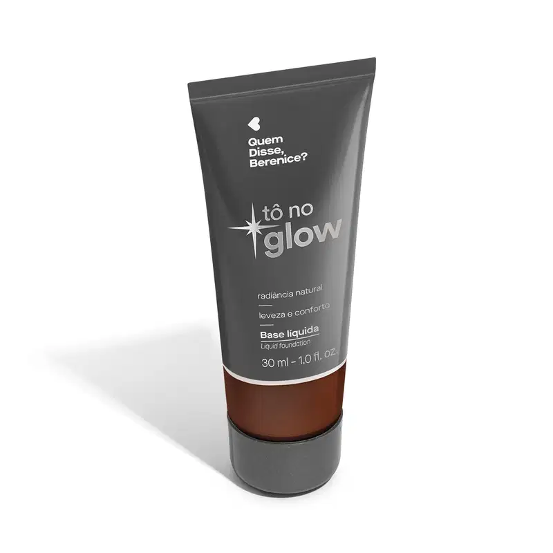 O produto apresentado é uma base líquida da marca Tô no Glow, com embalagem em tubo plástico de cor cinza escura. O rótulo exibe o nome da marca e o texto "Radiância natural, leveza e conforto" em letras brancas.