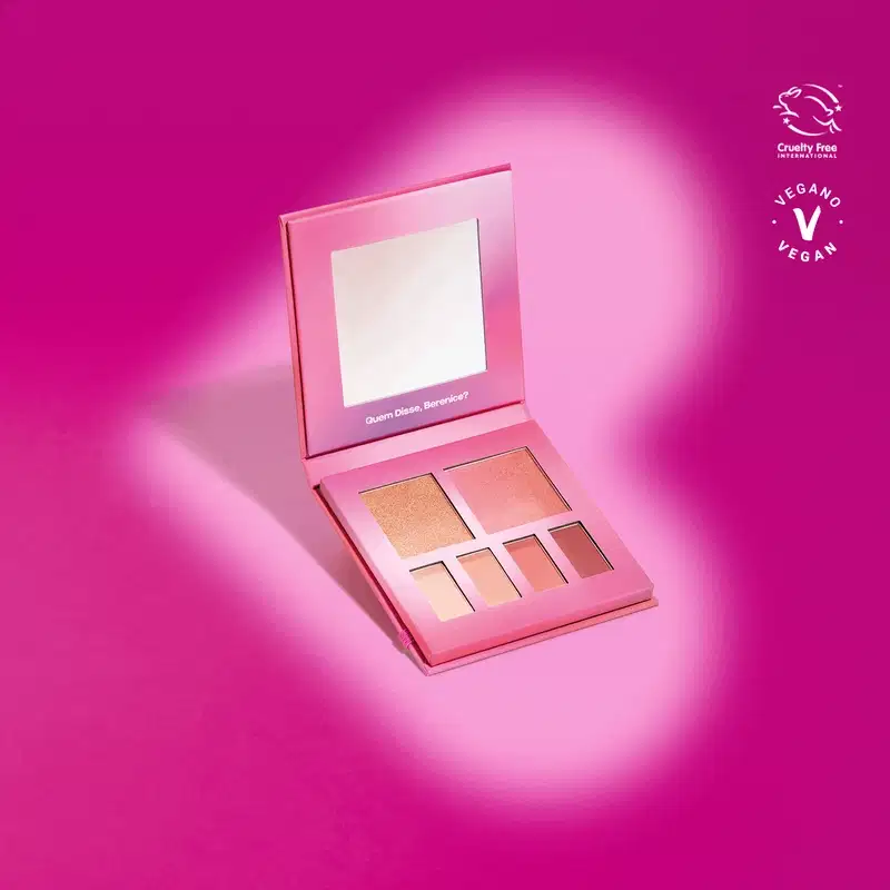 A paleta contém cinco sombras de diferentes tons de marrom e dourado, com um espelho embutido na tampa. O logotipo da marca "Vegano" e o selo "Cruelty Free" são visíveis na embalagem.